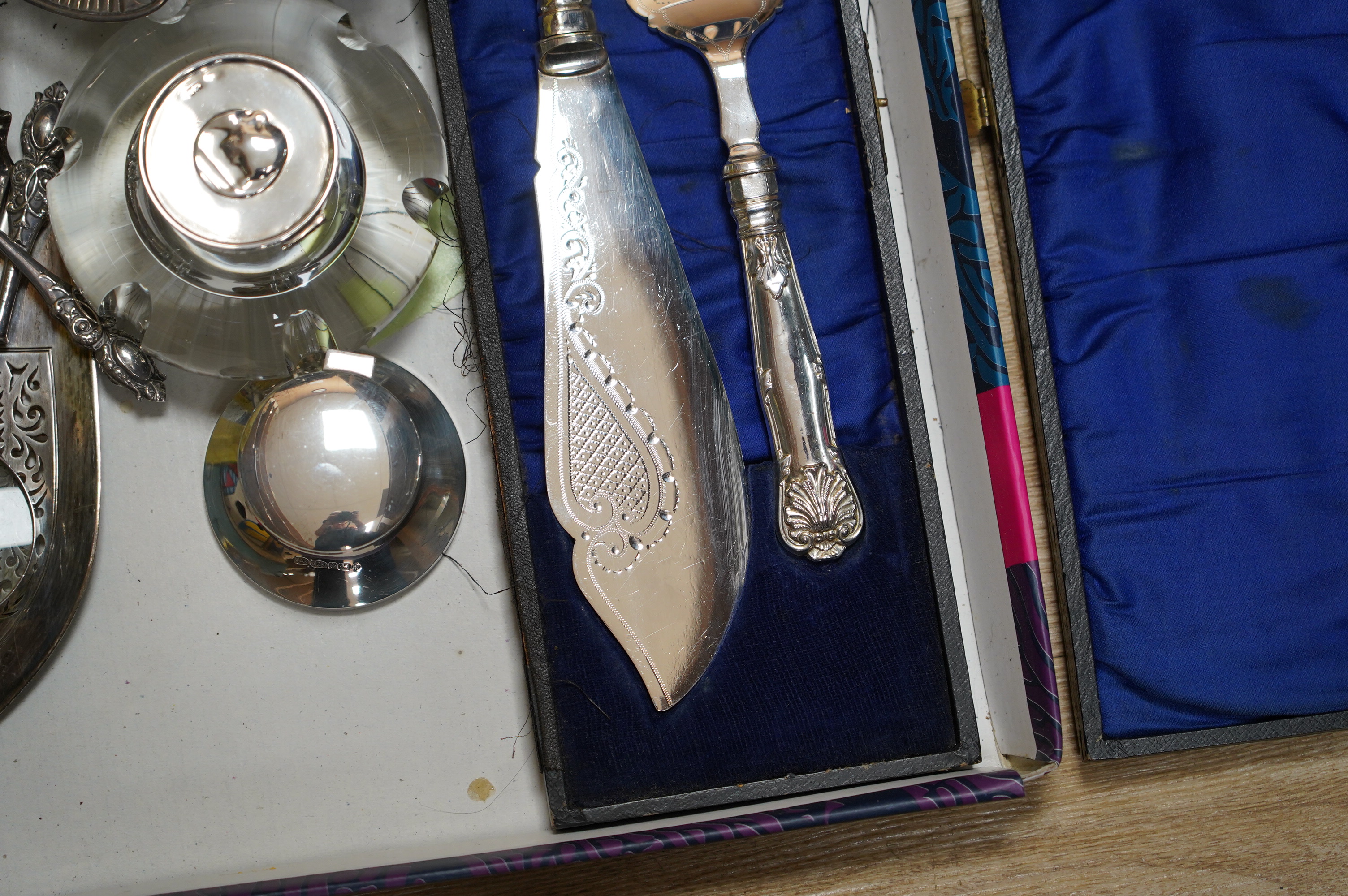 Sundry silver items including two inkwells, a William IV fiddle pattern fish slice, a pair of bonbon dishes and two handled magnifying glasses (one a.f.), together with a cased pair of plated fish servers. Condition - po